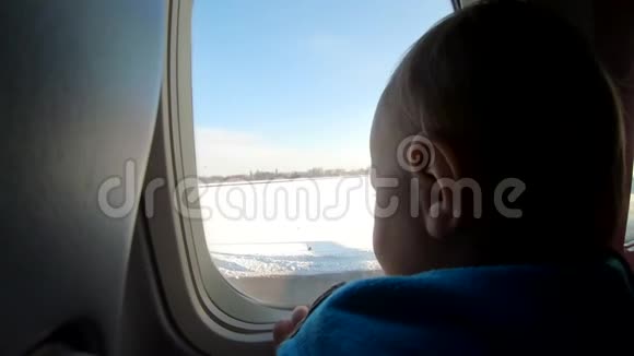 金发小男孩坐在飞机窗户附近看着视频的预览图