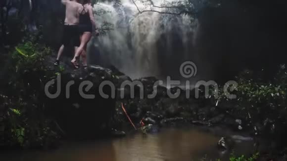 在洞穴瀑布下相爱的情侣一对情侣巴厘岛之旅做运动旅途空中射击旅行概念视频的预览图