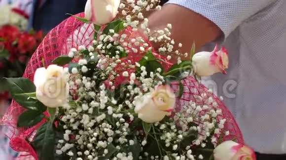 一个美丽的花朵和红玫瑰的女人手中的气味特写镜头鲜花作为节日的礼物视频的预览图