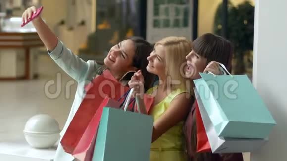购物愉快公司购物的女性在购物时用手机拍下自拍视频的预览图