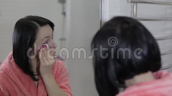 漂亮的黑发女人用棉花垫女人卸妆视频的预览图