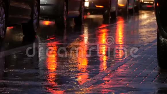 汽车在交通中站立前灯在雨中在沥青上视图下面晚上雨打水坑汽车的反射视频的预览图