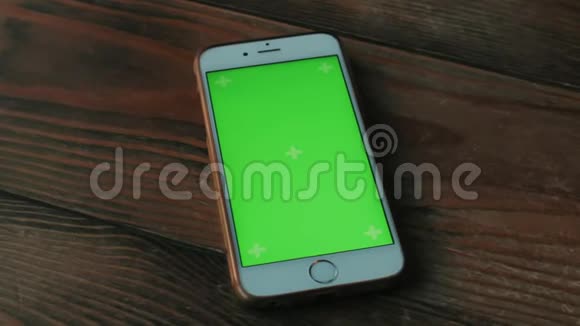 一个绿色屏幕的白色手机在咖啡馆的深棕色木桌上视频的预览图