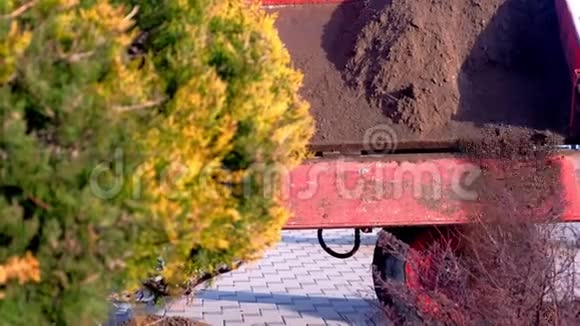 拖拉机把土从桶里倒在城市的床上视频的预览图