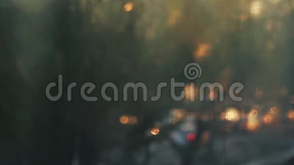 去焦夜城背景汽车红绿灯日落时分模糊的画面小小的春雨把水滴落在wi上视频的预览图