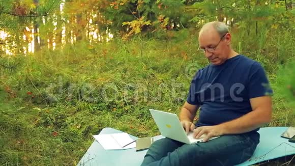 森林里的一个人在笔记本上写字在手机上说话视频的预览图
