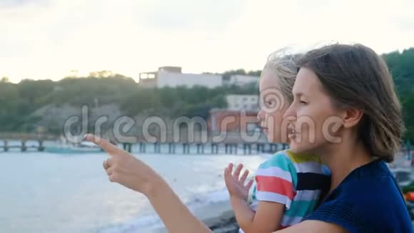 美丽的女人带着儿子望着海边的霍里森刮风的天气视频的预览图