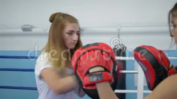 运动爱好年轻女子在健身房为打拳击的女孩握拳爪视频的预览图