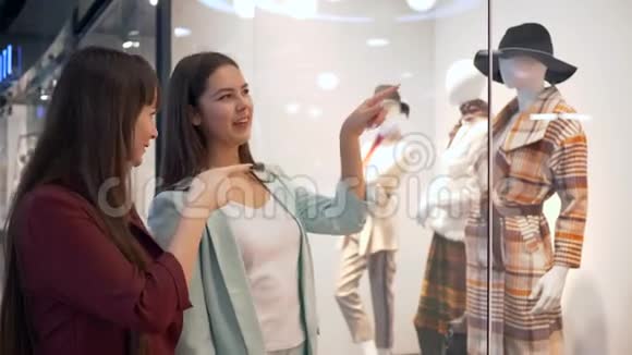 购物者的生活方式快乐的女朋友在商店橱窗里讨论时尚的人体模特新系列服装视频的预览图