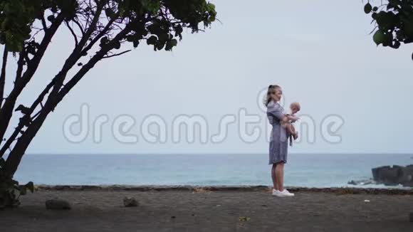 专注的母亲和婴儿拥抱花费粘合质量的时间观察明亮的蓝色云景用心做父母视频的预览图