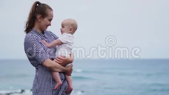 美丽的母亲吻女儿的肖像在海洋和海滩背景假期里的幸福家庭旅行妈妈拥抱视频的预览图