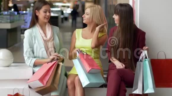 购物愉快漂亮的女孩带着很多包在黑色星期五坐在购物中心里享受购物的乐趣视频的预览图