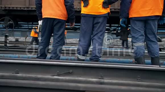 铁路工人正站着看着一列经过的火车腿部特写穿着橙色工作服的工人视频的预览图