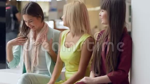 季节性大减价快乐的女孩们拿着一堆彩色纸袋坐在购物中心视频的预览图