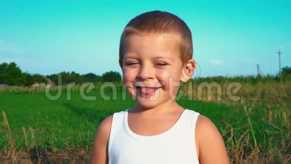 四岁的男孩穿着一件白色的t恤微笑着把舌头伸进相机里然后移开视线一个可爱的孩子的肖像视频的预览图
