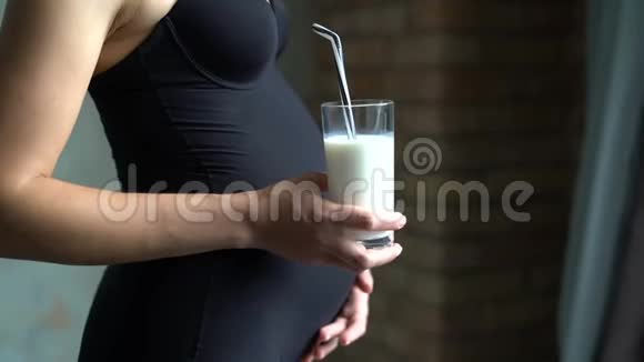 在女性腹部背景上特写一杯牛奶孕妇拿着4K玻璃杯视频的预览图
