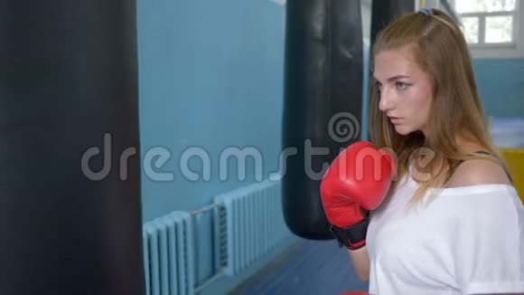 运动爱好运动女子拳击手套训练与拳击袋在健身室视频的预览图