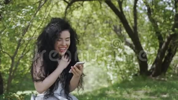 快乐的女人用手机和朋友聊天在花园里放松视频的预览图