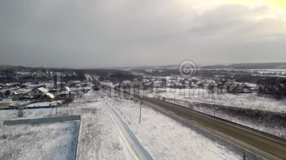 公路穿越河上村庄的鸟瞰图冬天和降雪视频的预览图