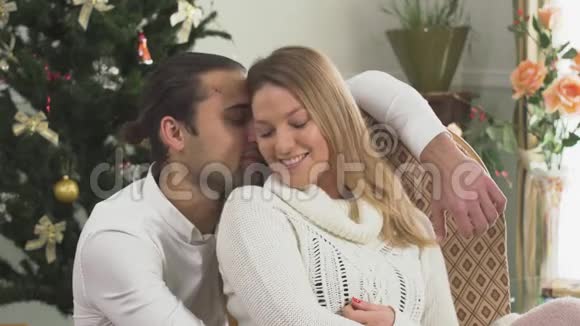一对幸福的情侣坐在家中圣诞树旁的画像妻子和丈夫在一起很幸福爱情视频的预览图