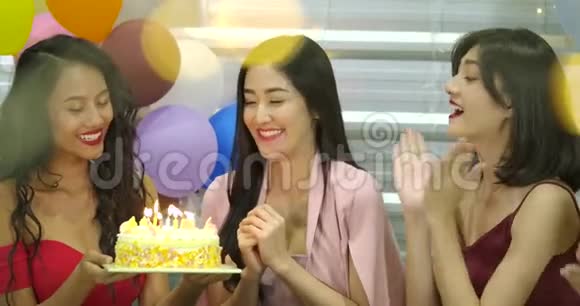 年轻女子的生日女孩正在许愿在蛋糕上吹蜡烛在朋友祝贺时拍手视频的预览图