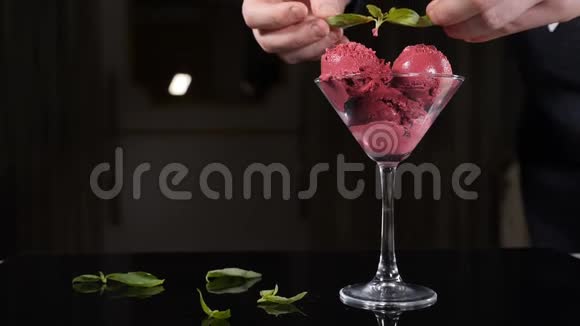 一位厨师用薄荷叶装饰一个冰淇淋盘餐厅提供冰淇淋甜点厨师装饰薄荷叶视频的预览图