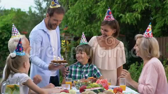 友好的家庭祝贺小男孩生日用蜡烛送蛋糕视频的预览图