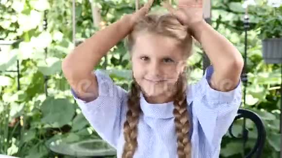 可爱的女孩在一个开放的露台上玩用手展示耳朵快乐的童年笑享受晴天4k视频的预览图