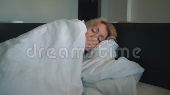 一个感冒的女人感觉不好吹进鼻子里裹着一条白色的毯子医生医疗帮助视频的预览图