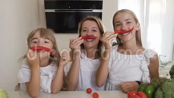 两个姐姐和他们的母亲穿着白色的衣服在家里的厨房里玩辣椒女孩视频的预览图
