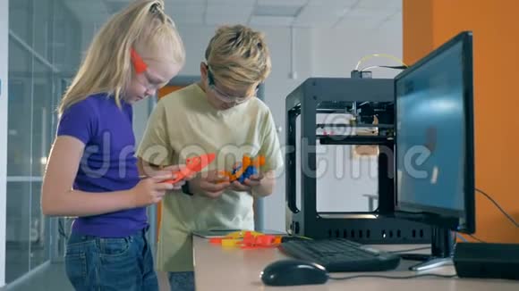 学生在学校现代实验室持有3D打印元素发明概念视频的预览图