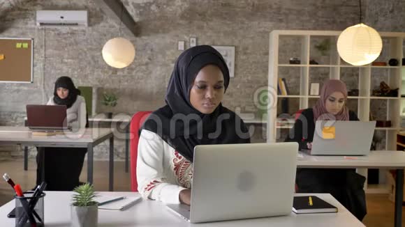 年轻的非洲穆斯林妇女头戴头巾手提电脑打字咳嗽三个美丽的穆斯林妇女在现代工作视频的预览图