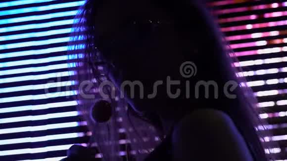 在迪斯科俱乐部的光照下带棒棒糖的太阳镜上有魅力的模特视频的预览图