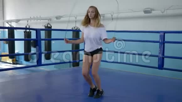 穿短短裤的肌肉女运动员用跳绳来保持拳击场的健康视频的预览图
