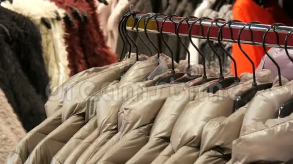 在商场购物中心的服装店里各种各样的女式冬季夹克衫挂在衣架上视频的预览图