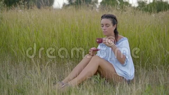美丽的女人在草地上喝咖啡视频的预览图