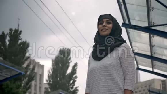 年轻的穆斯林妇女戴着头巾等待火车n火车站下雨宗教概念城市概念天气预报视频的预览图