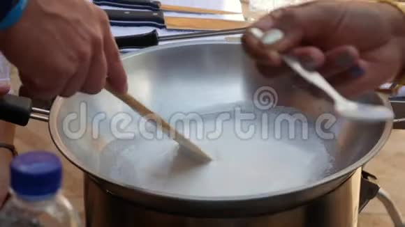男性手在炒锅中搅拌沸腾的椰奶一步步烹制泰国糯米泰国菜特写镜头4k视频的预览图