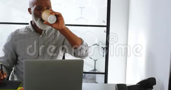 在办公桌4k上商人一边喝咖啡一边使用平板电脑视频的预览图