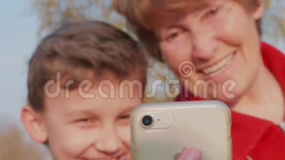 年长妇女和少年男孩用手机自拍视频的预览图