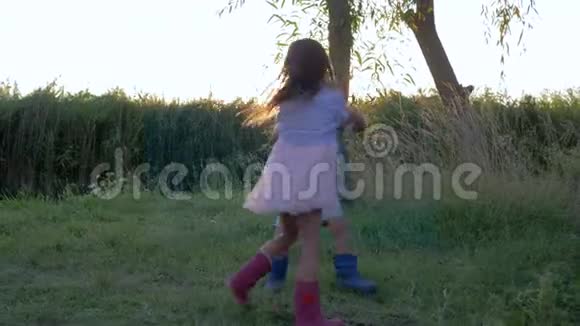 孩子们在户外玩得很开心可爱的小男孩和女孩在绿草上旋转视频的预览图