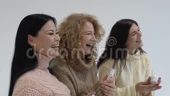 一群三个女人开心地笑着穿毛衣的女人选择化妆品三个朋友购物慢动作视频的预览图