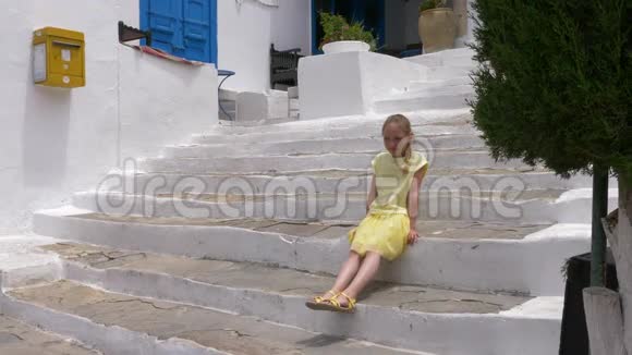 度假城市夏季散步时坐在白色楼梯上的少女视频的预览图