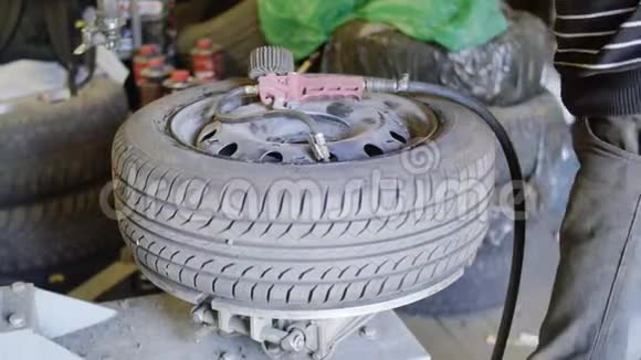 男车技师在汽车维修服务车库完成车轮上的抽轮胎视频的预览图