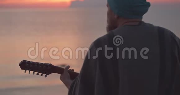 日出时在海边弹吉他的年轻人视频的预览图
