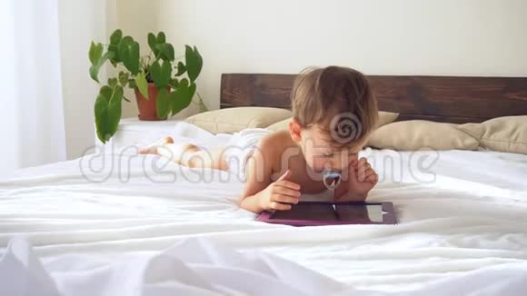 小男孩看着躺在床上的平板电脑视频的预览图