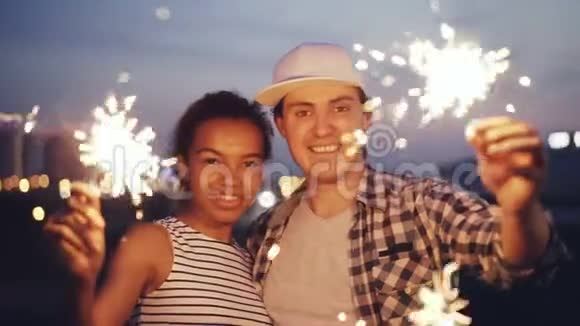 一对漂亮的多种族夫妇的慢镜头肖像非裔美国女孩和白人男子手持孟加拉灯视频的预览图