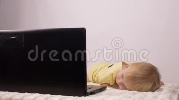 小女孩躺着看电脑屏幕笔记本电脑白色背景看动画片视频的预览图