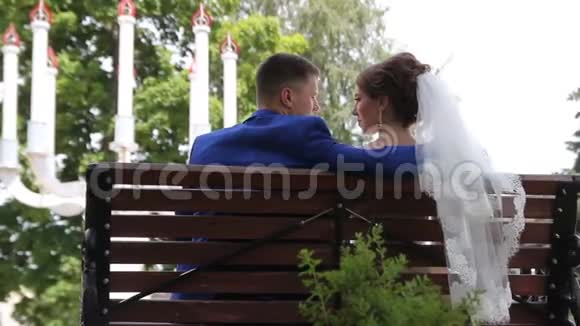 公园里的新娘和新郎坐在长凳上视频的预览图