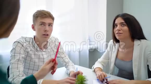 一个男人和三个女孩坐在桌子上在学校图书馆里互相交谈视频的预览图